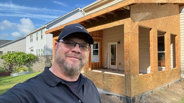 A man is taking a selfie in front of a house under construction.