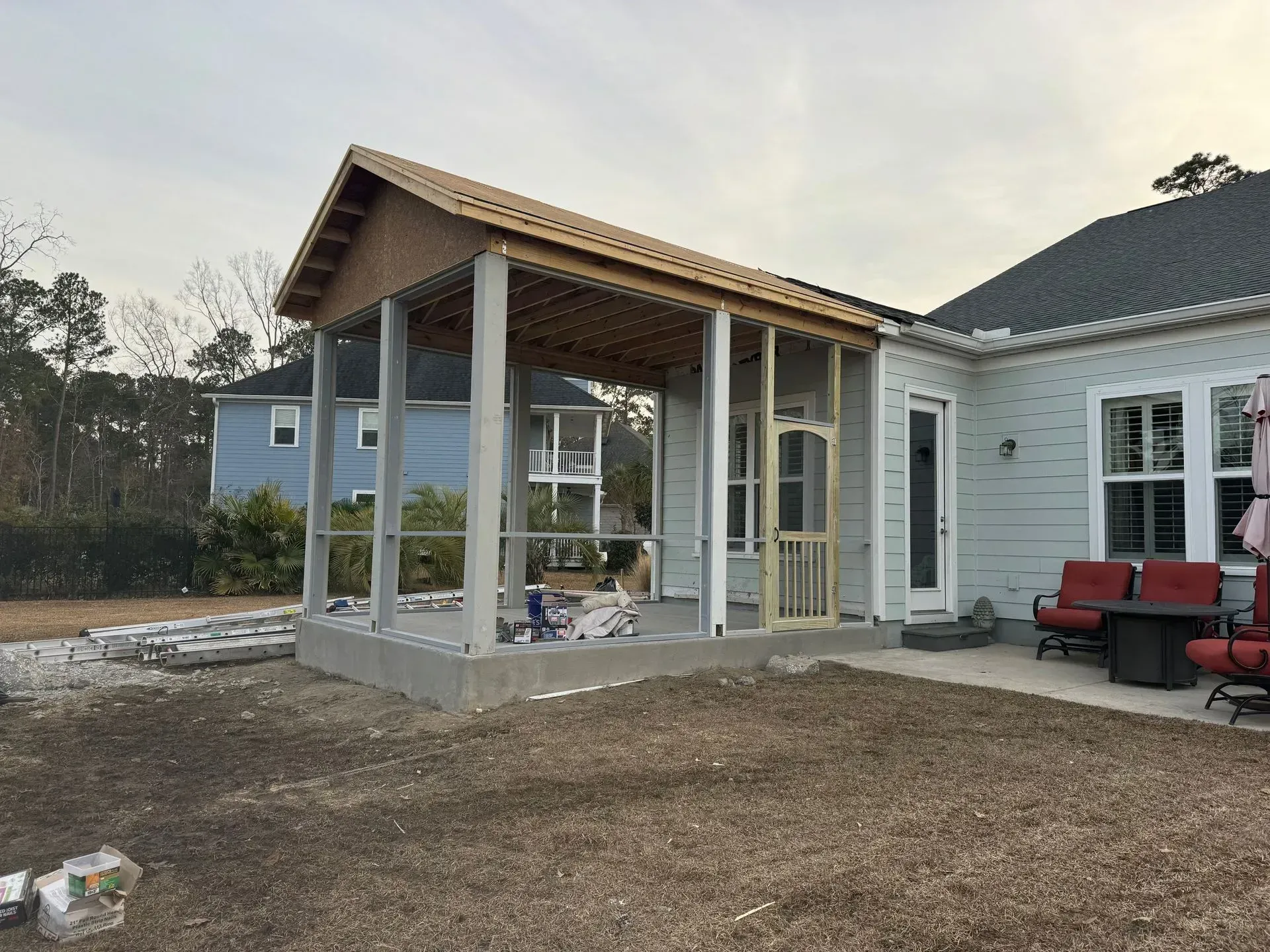 A screened in porch is being built on the side of a house.