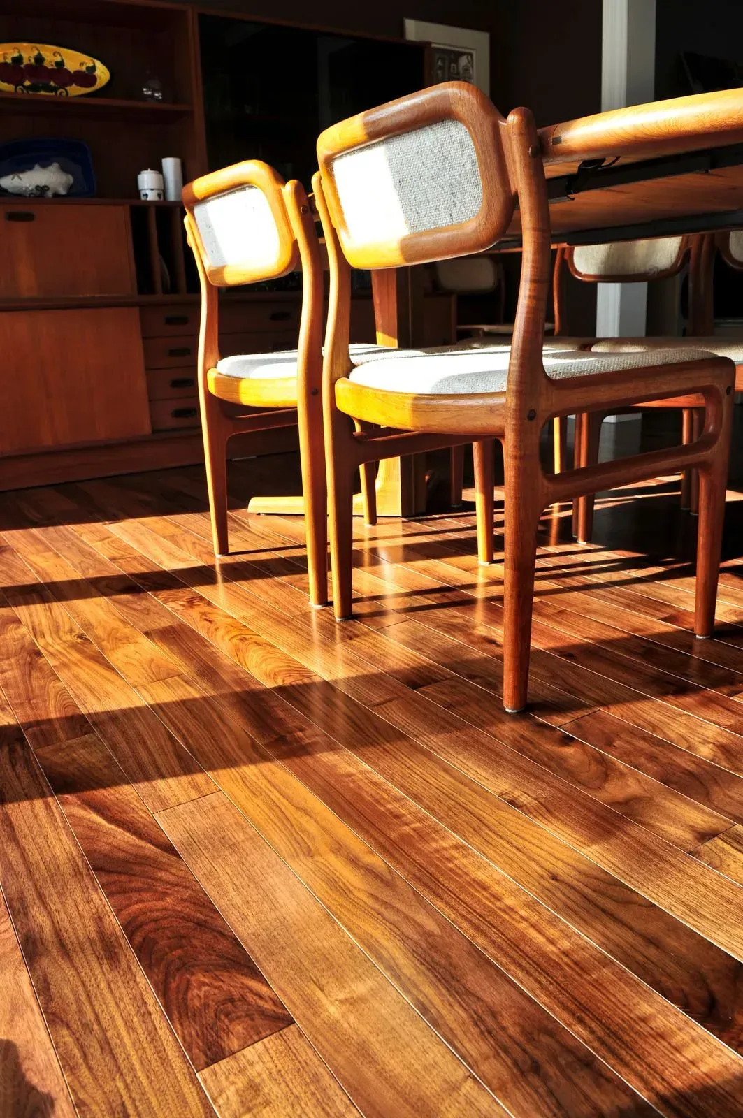 A wooden floor with chairs and a table in the background