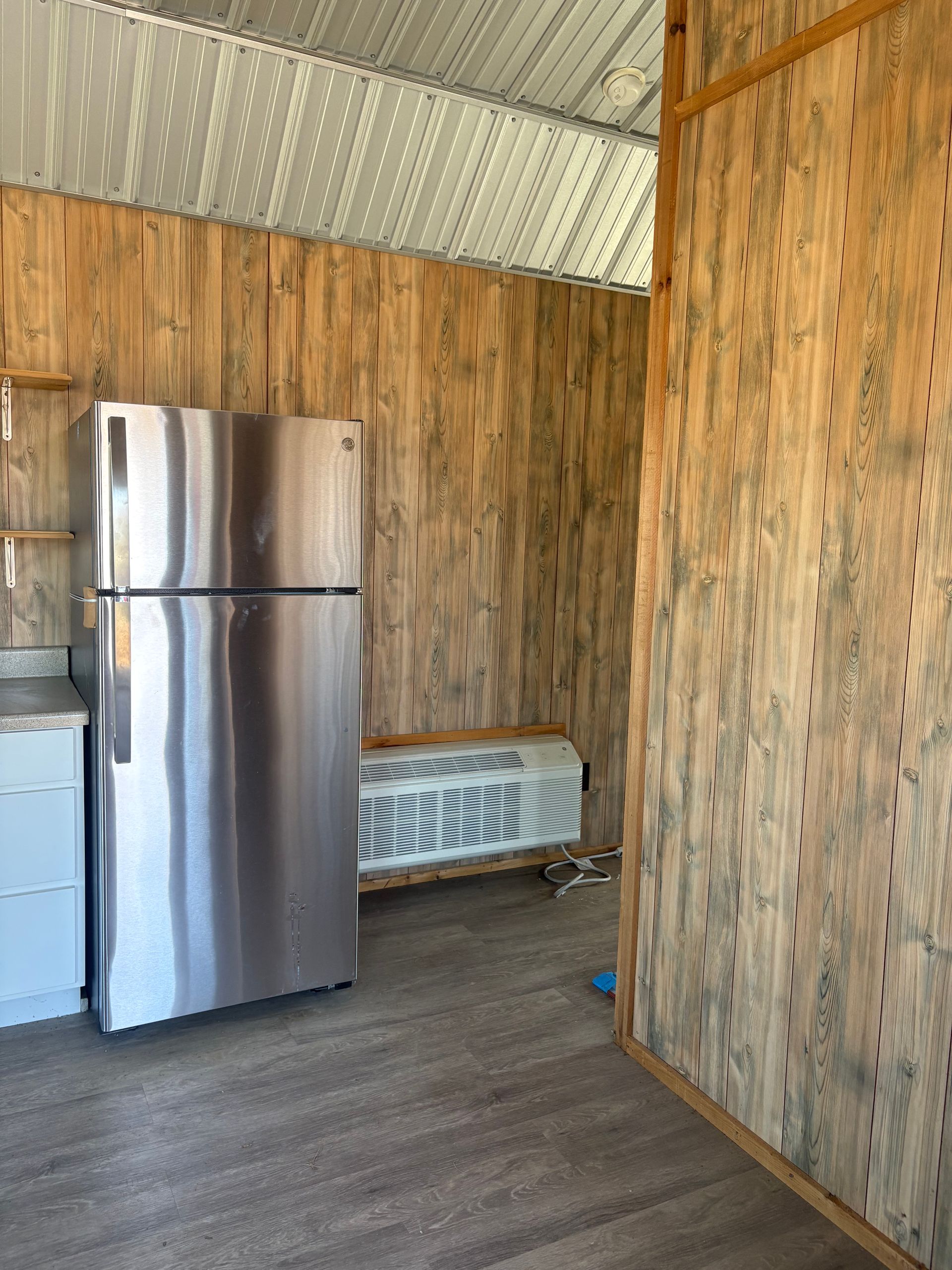 Interior with stainless steel fridge, wood-paneled walls, and a heater.