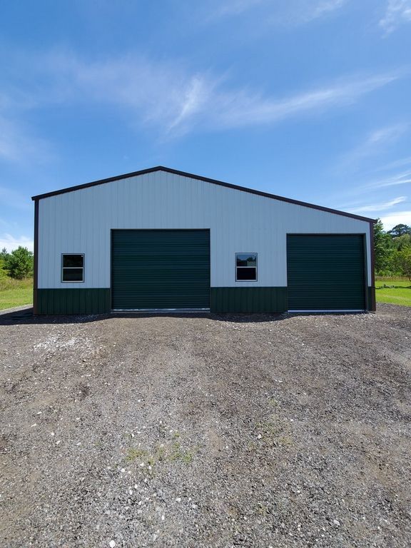 Metal building with green doors, white walls, and a blue sky backdrop.