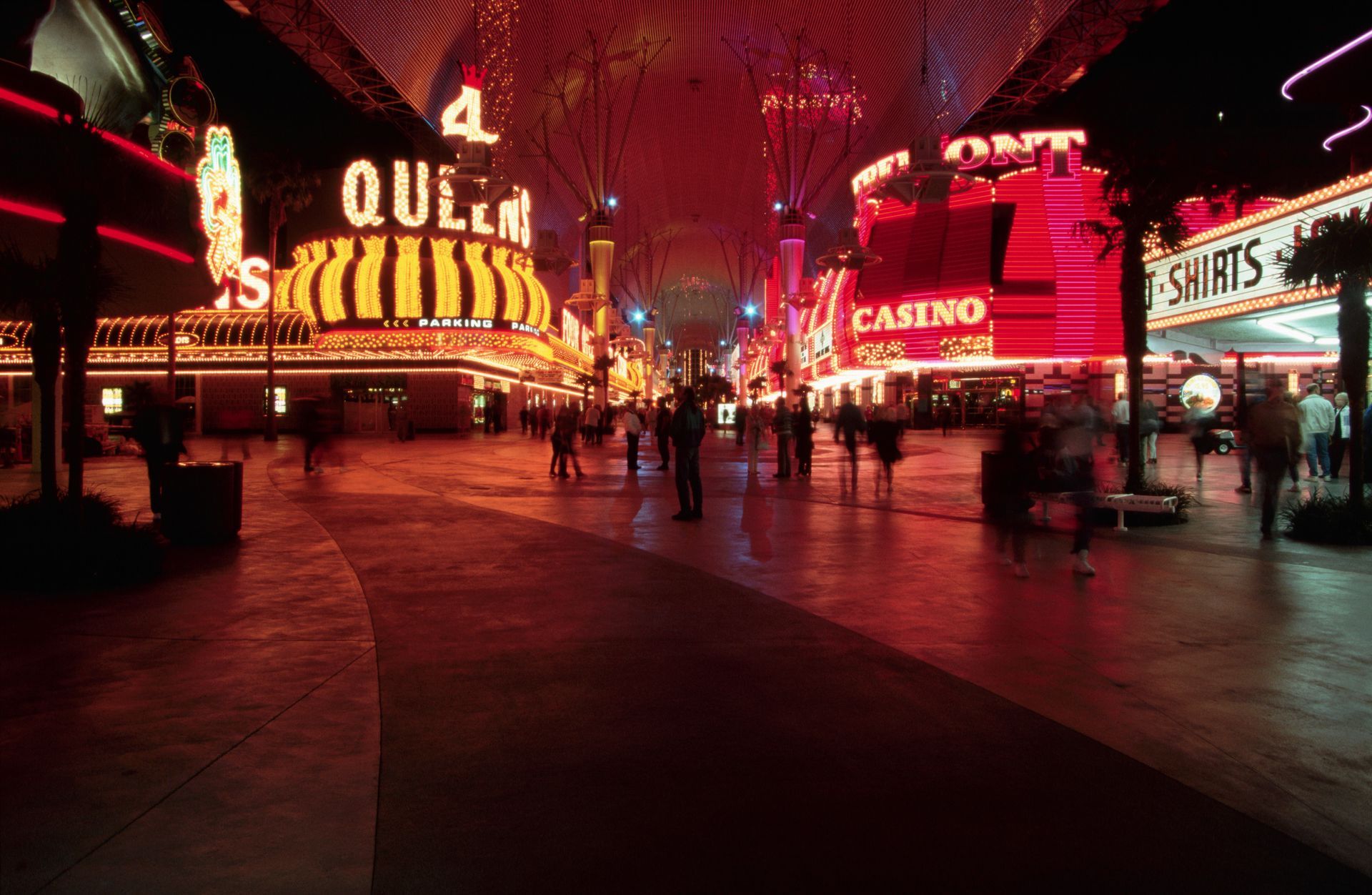 A group of people are walking down a street in front of a casino.