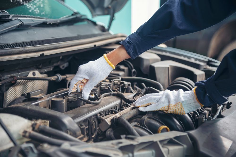 Mechanic in Blue Workwear and Gloves Inspecting a Car Engine — Warners Bay Tyre & Mechanical in Warners Bay, NSW
