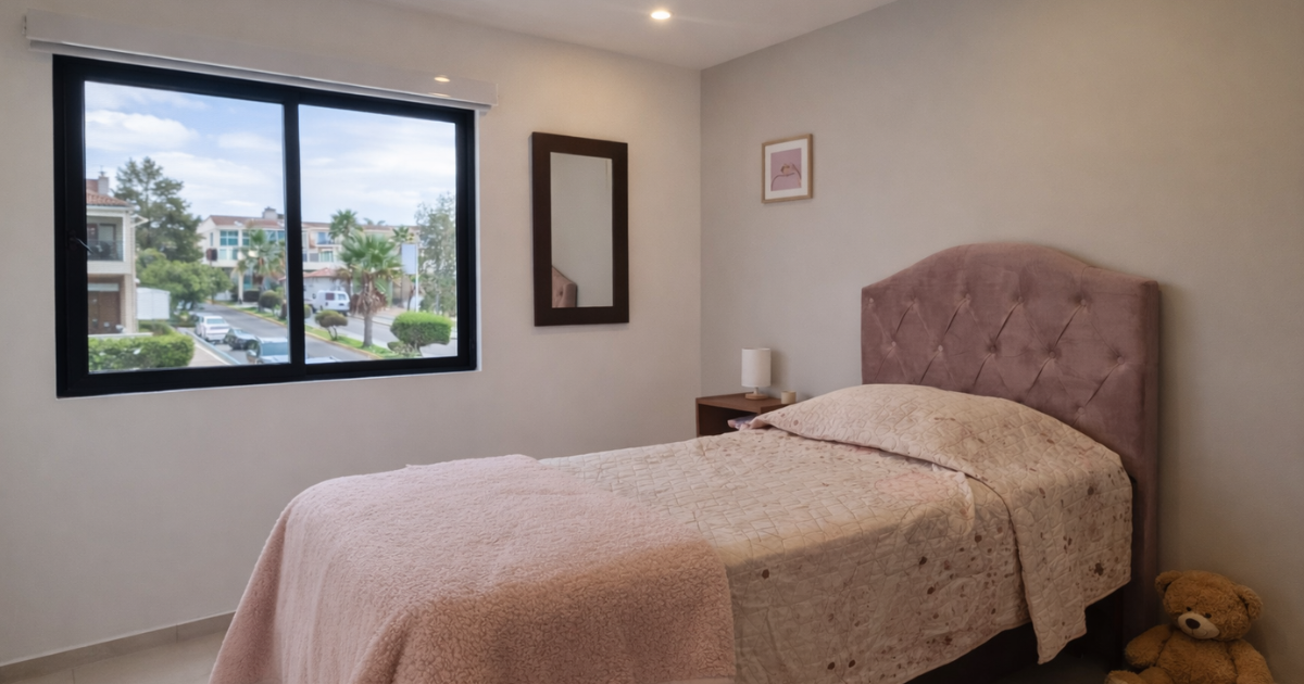 Dormitorio con cama rosa, ventana, espejo, mesa pequeña y osito de peluche para casas en Tijuana