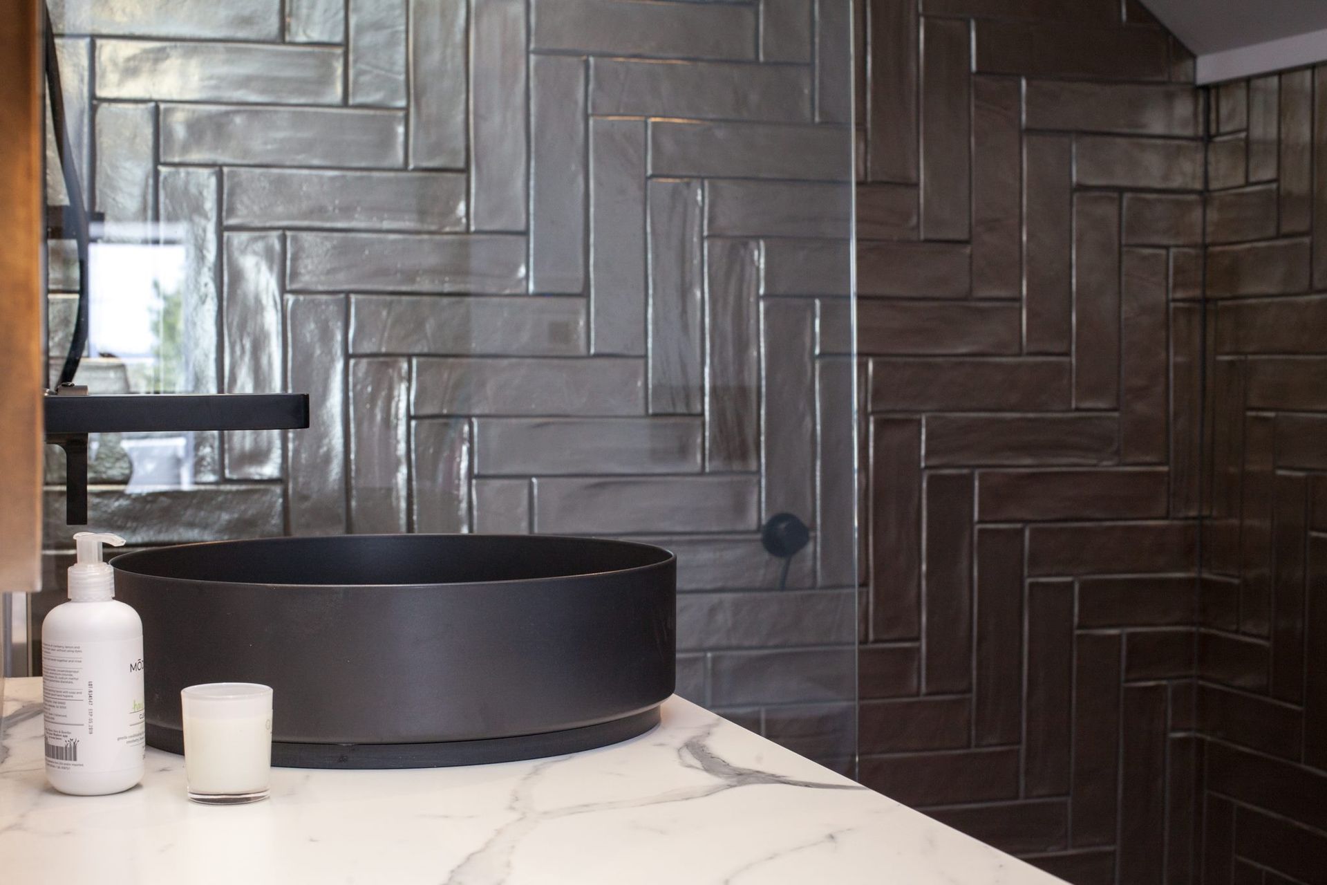 A bathroom with black tiles and a black sink