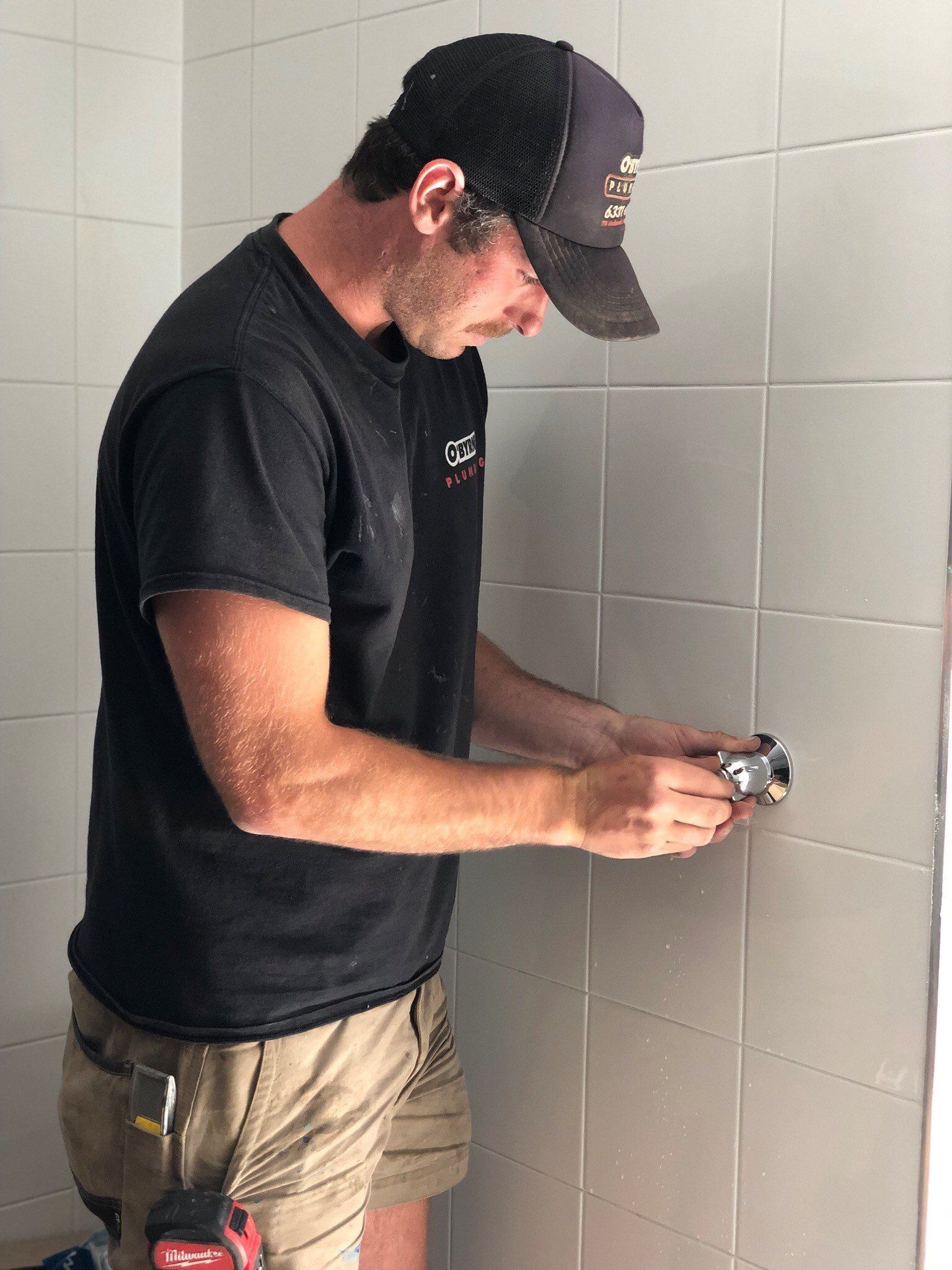 A man in a yellow vest is working on a bathroom sink.
