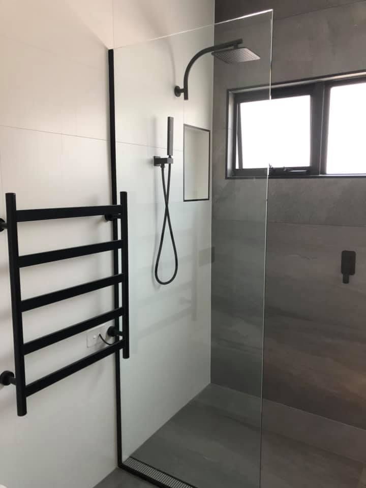 A bathroom with a walk in shower and a towel rack