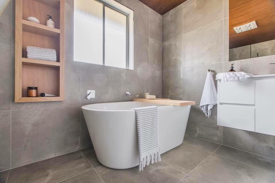 A bathroom with a bathtub , sink , and window.