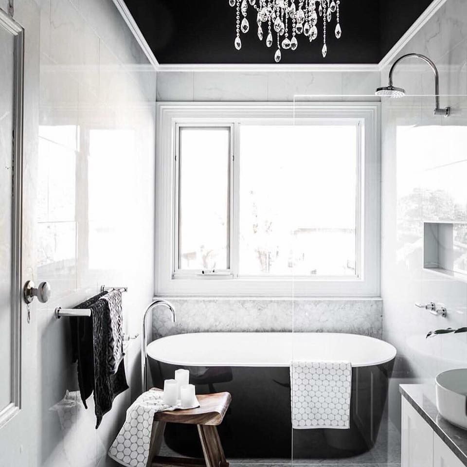 A bathroom with a bathtub and a chandelier hanging from the ceiling.
