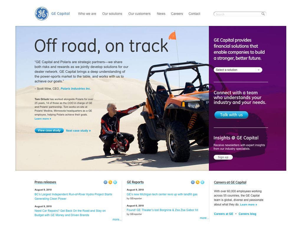 A man is kneeling next to a four wheeler on a website.