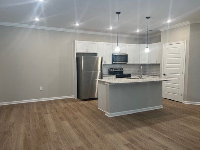 Kitchen with light wood floors, gray cabinets, stainless steel appliances, and a kitchen island.