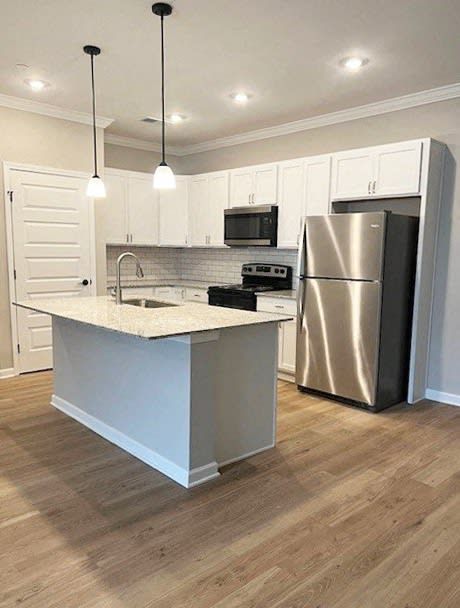 Modern kitchen with white cabinets, stainless steel appliances, and a gray island.