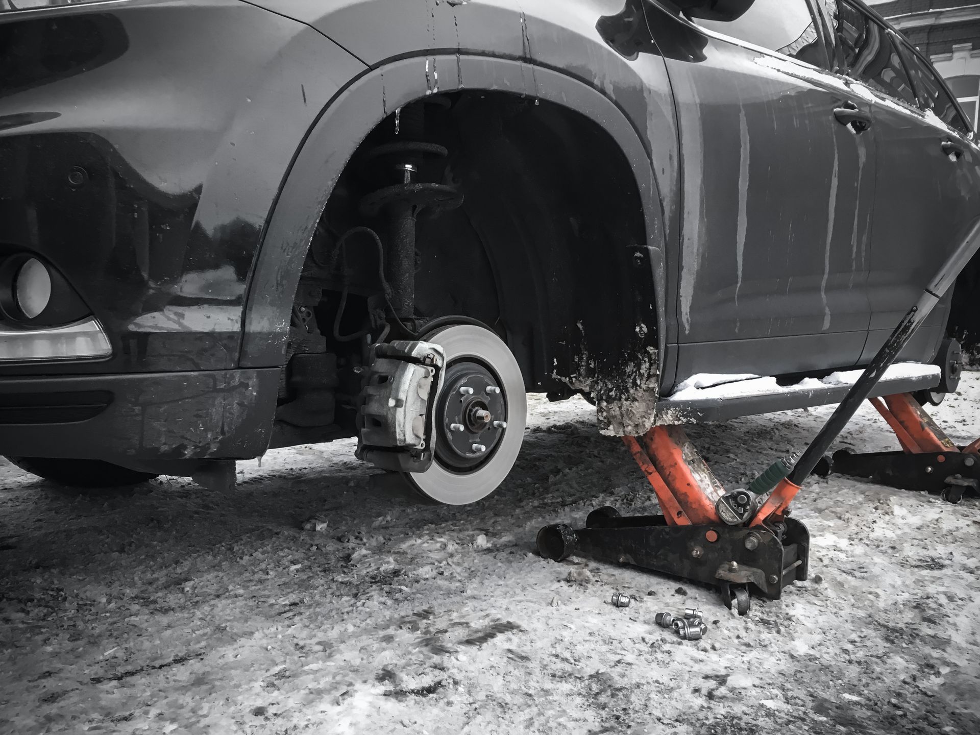 A black SUV on a car stands waiting for a brake repair on a wintry road.