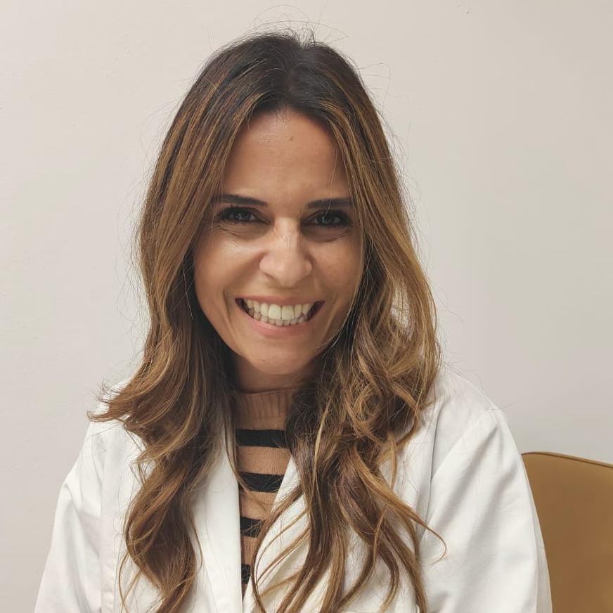 Una donna in camice bianco sorride alla telecamera.