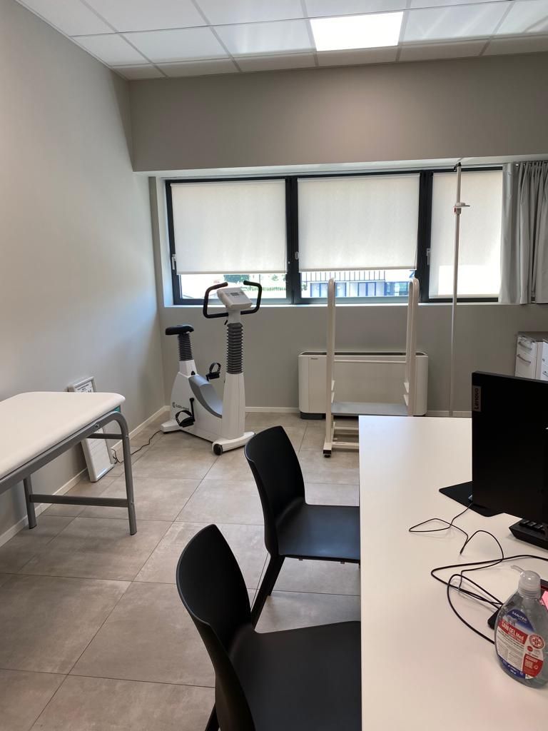 Una stanza con scrivania, sedie, bicicletta e computer.