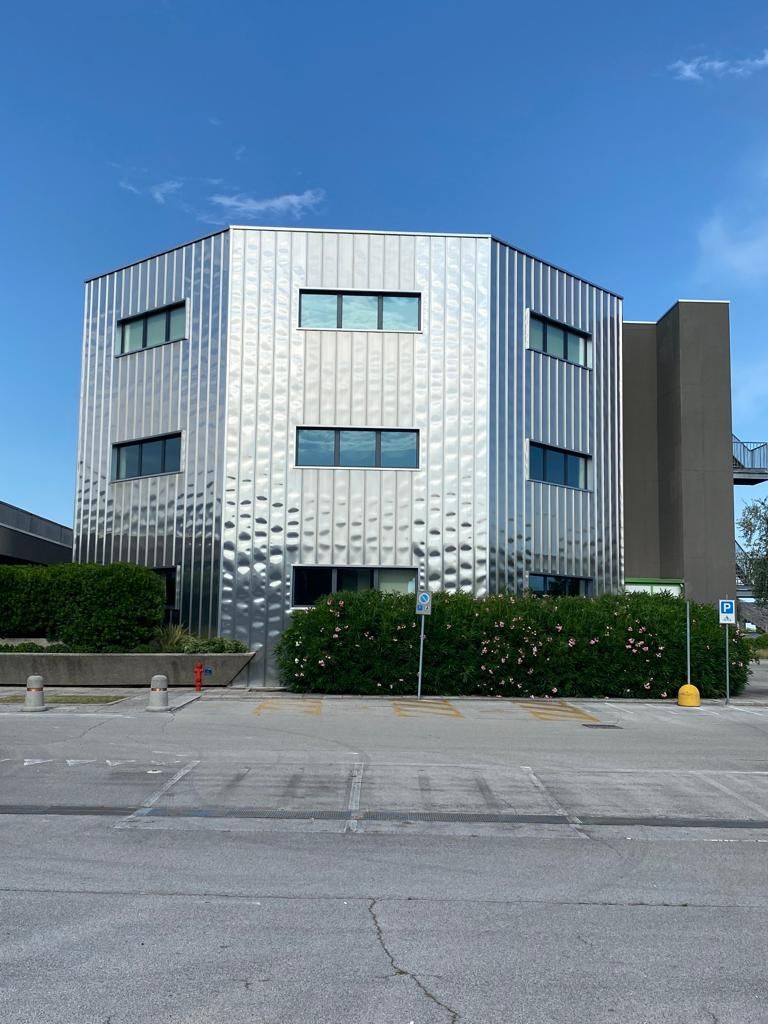 Un edificio argentato con un parcheggio di fronte