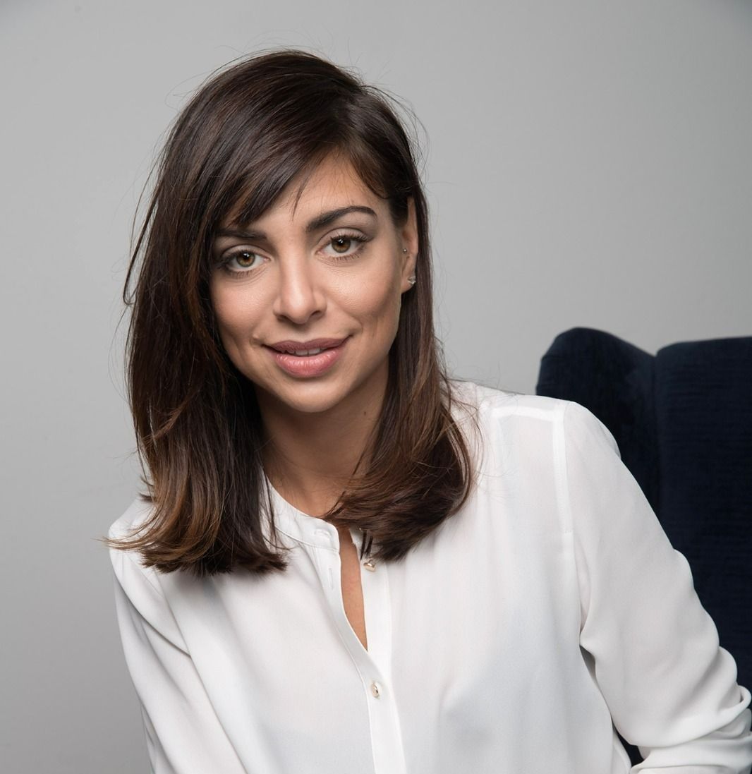 Una donna è seduta su una sedia e indossa una camicia bianca