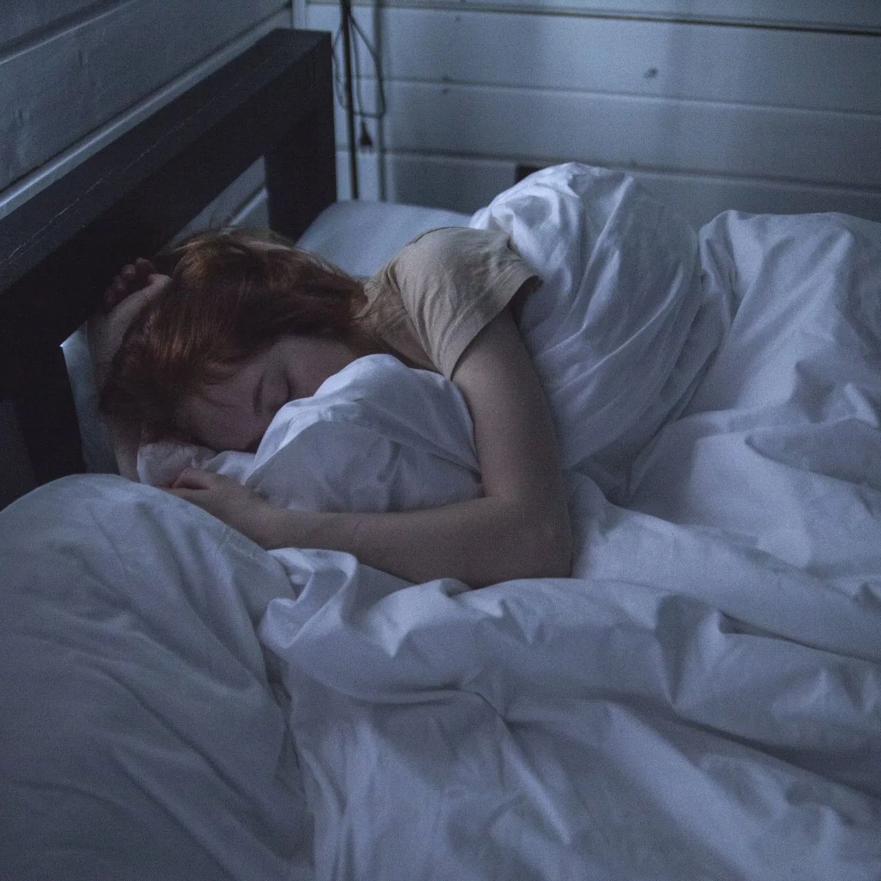Una donna dorme in un letto con lenzuola bianche