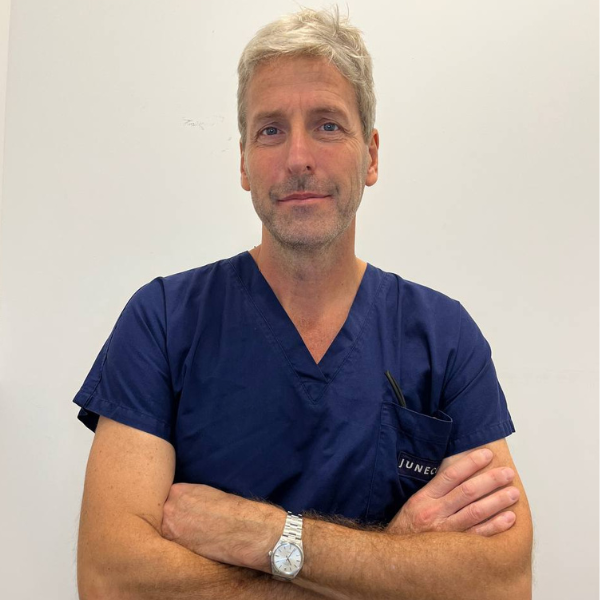 Un uomo in camice blu ha le braccia incrociate