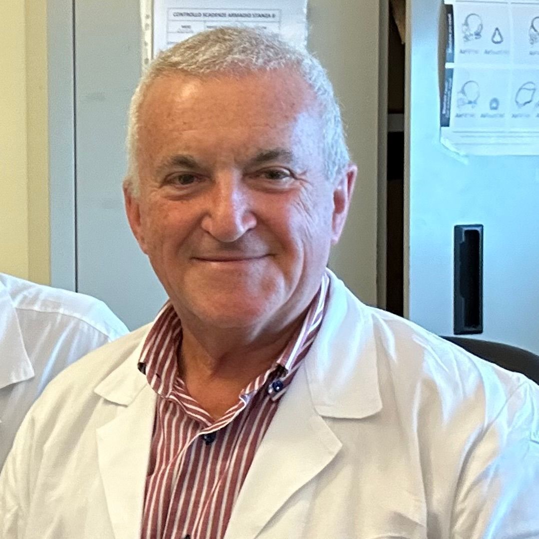 Un uomo in camice da laboratorio e camicia a righe sorride