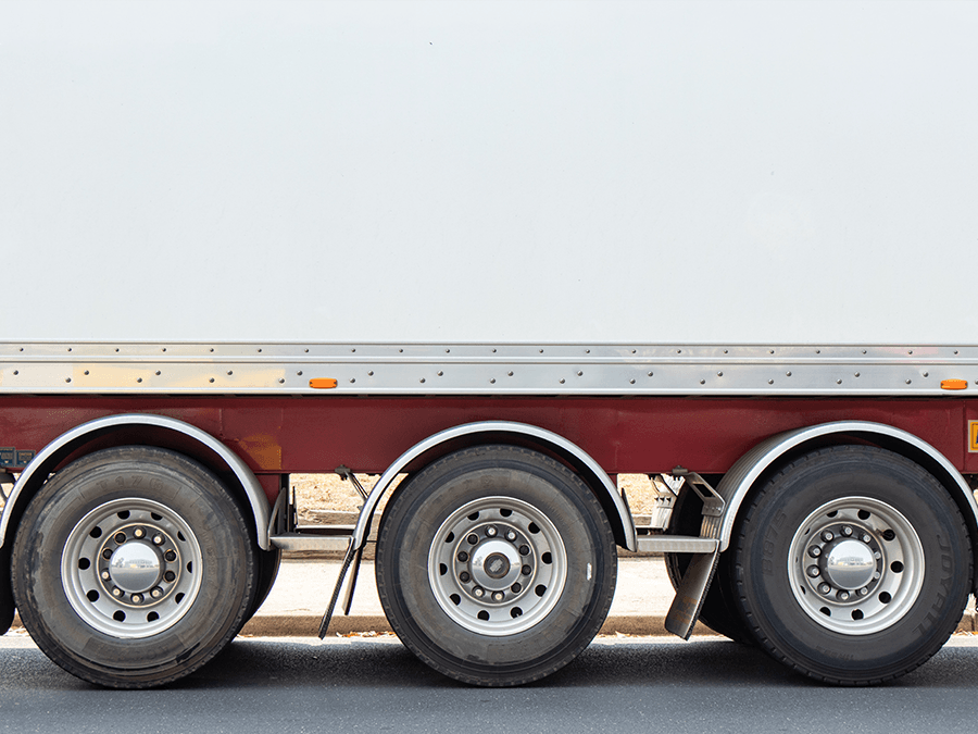 A semi truck with three tires is parked on the side of the road.