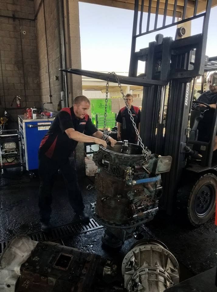 A man is working on a forklift in a garage.