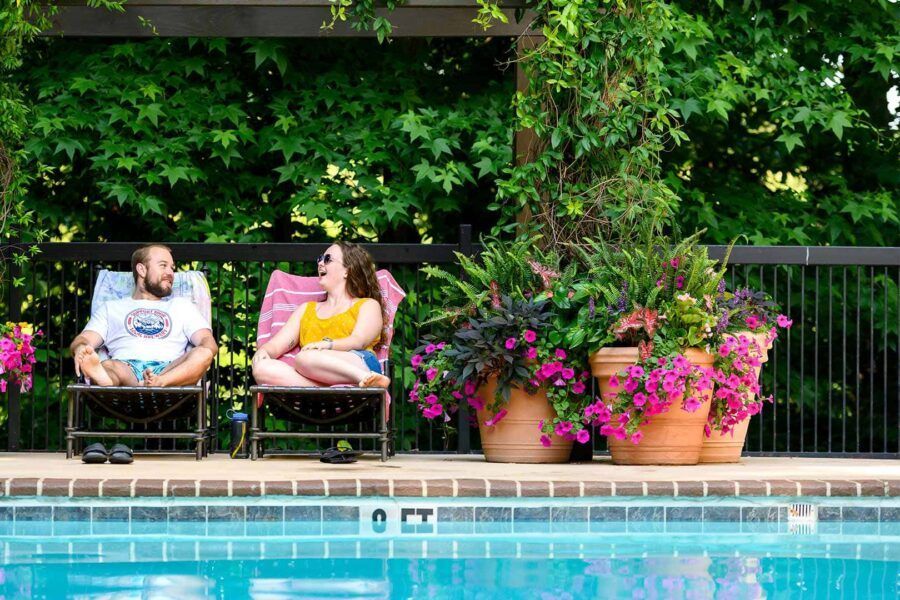 A man and a woman are sitting in lounge chairs next to a swimming pool.