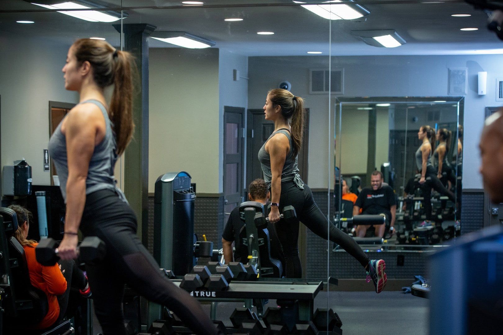 A woman is lifting a dumbbell in a gym.