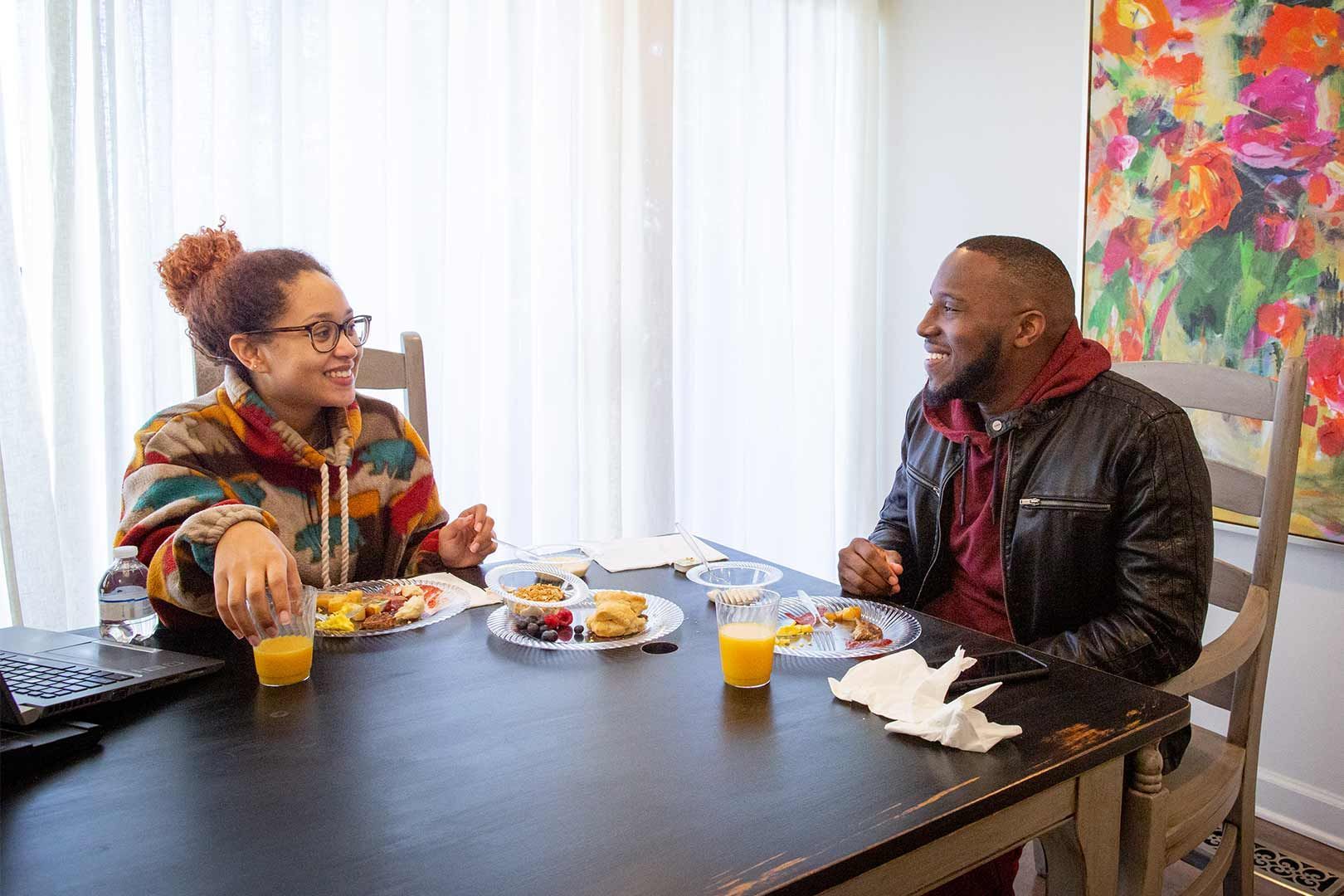 A man and a woman are sitting at a table eating food.