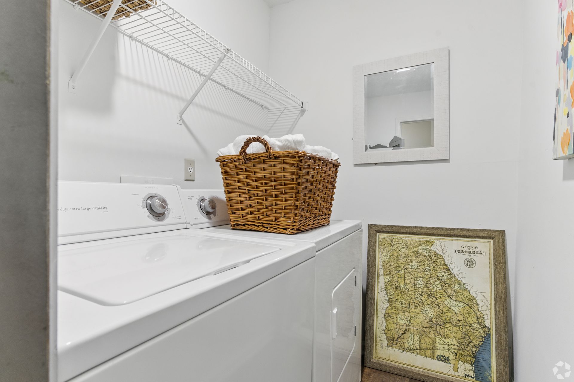 Laundry room with a washing machine, basket of towels, mirror, and map.