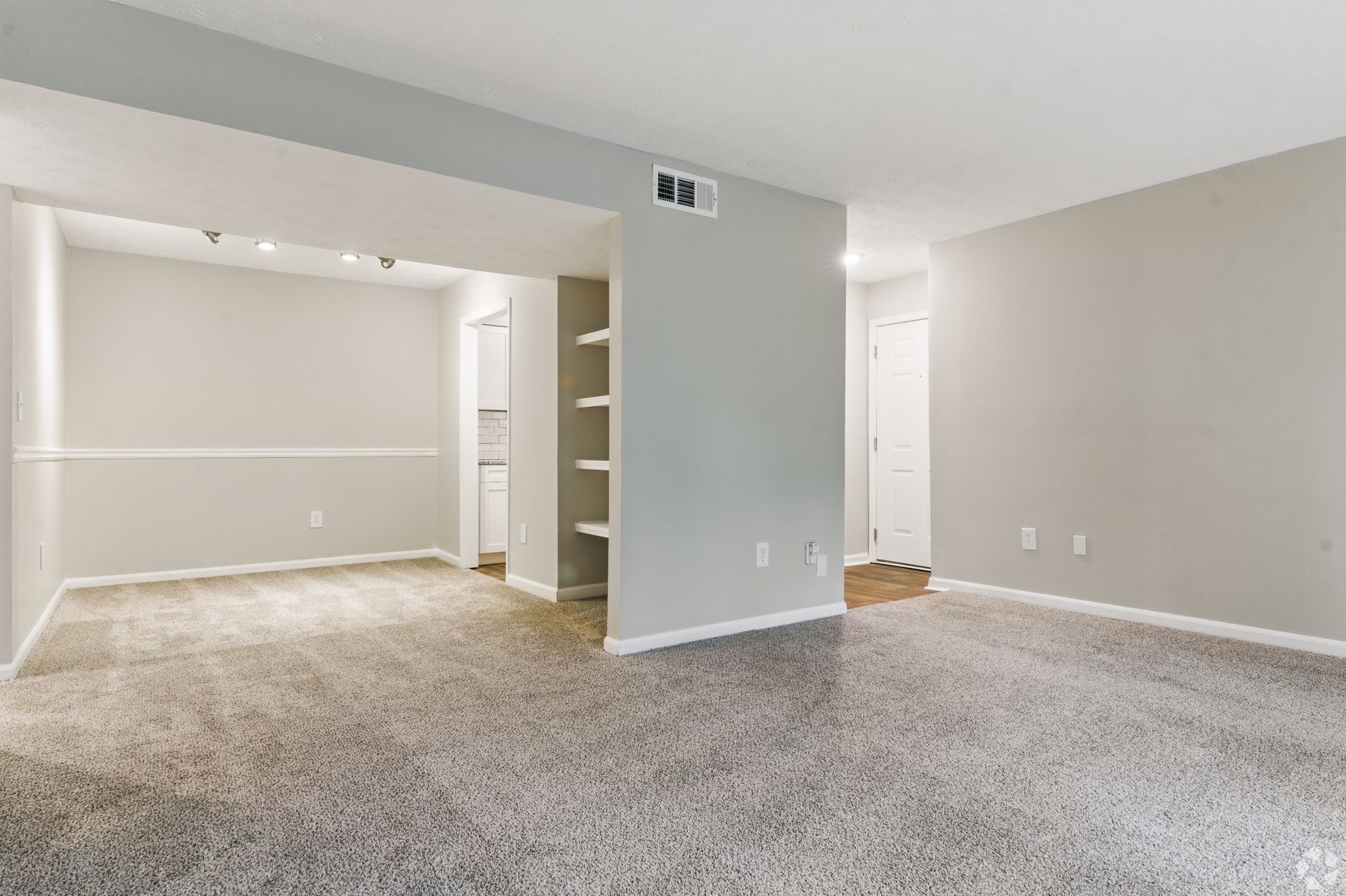 Empty apartment interior with gray walls, carpet, and an open layout.