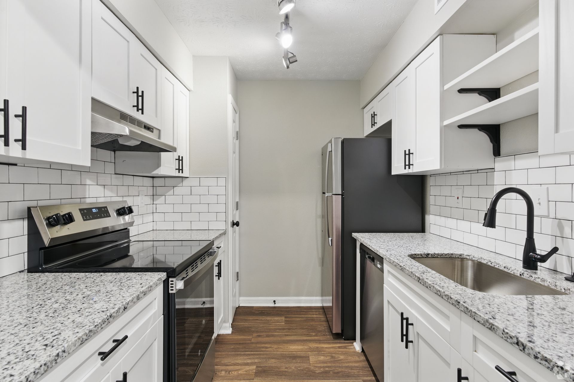 Bright white kitchen with black appliances, cabinets, and hardware, and wood-look floors.