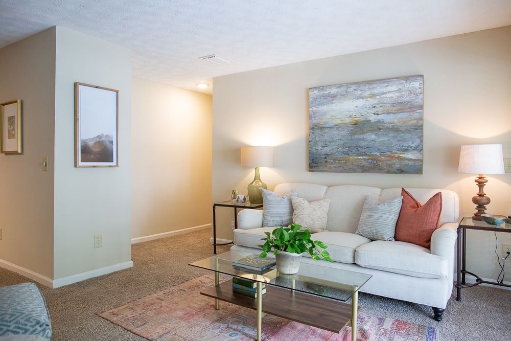 A living room with a couch , coffee table , lamps and a painting on the wall at Kinstone River Apartment Homes, offering 1, 2, and 3 bedroom apartments near The Battery, Atlanta, GA.