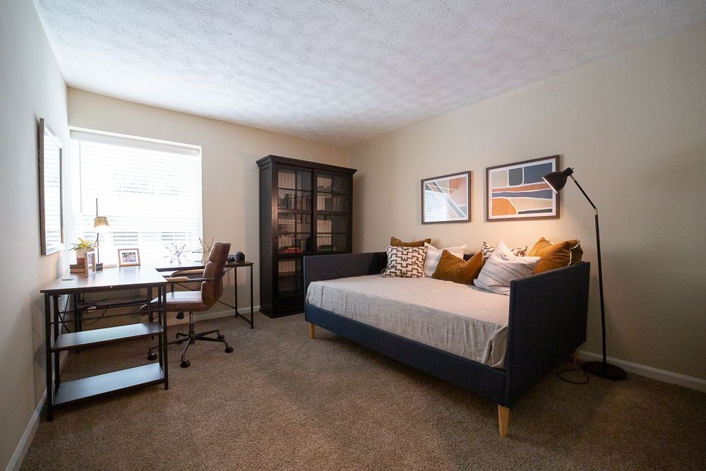 A bedroom with a day bed , desk and chair at Kinstone River Apartment Homes, offering 1, 2, and 3 bedroom apartments for rent in Atlanta, GA.