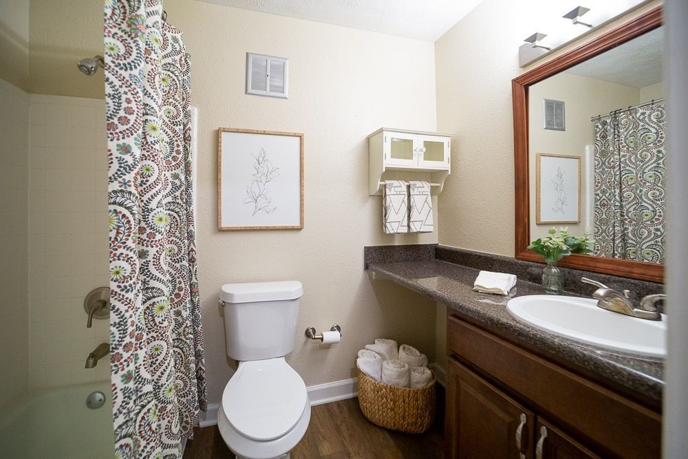 A bathroom with a toilet , sink , and shower curtain at Kinstone River Apartment Homes, offering 1, 2, and 3 bedroom apartments in Atlanta, near Chattahoochee River.