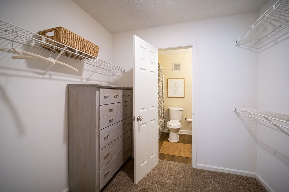 A walk in closet with a dresser and a toilet at Kinstone River Apartment Homes, offering 1, 2, and 3 bedroom apartments for rent in Atlanta, GA.
