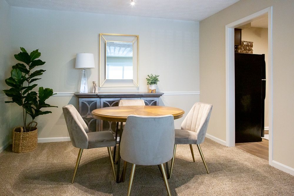 A dining room with a table and chairs, and a mirror on the wall at Kinstone River, offering apartments in Cumberland, GA.