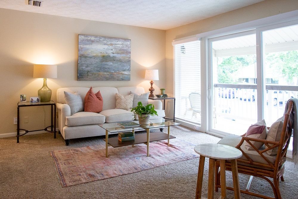 A living room with a couch, chair, coffee table, and sliding glass doors at Kinstone River Apartment Homes, offering 1, 2, and 3 bedroom apartments in Atlanta, GA.