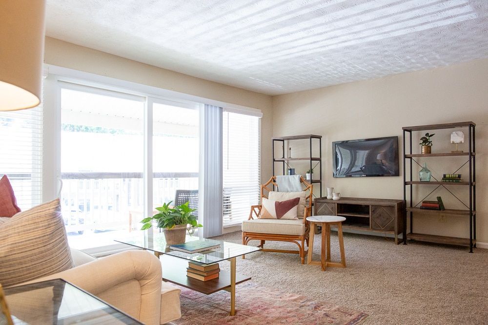 A living room with a couch, chair, coffee table, and television at Kinstone River, offering apts for rent in Atlanta, GA.