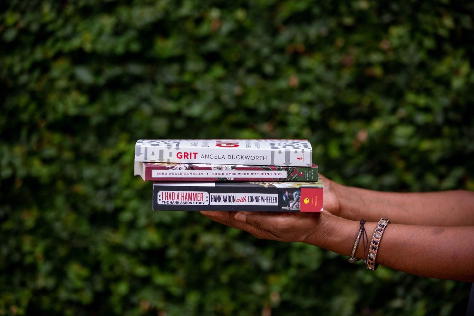 A person is holding a stack of books in their hands.