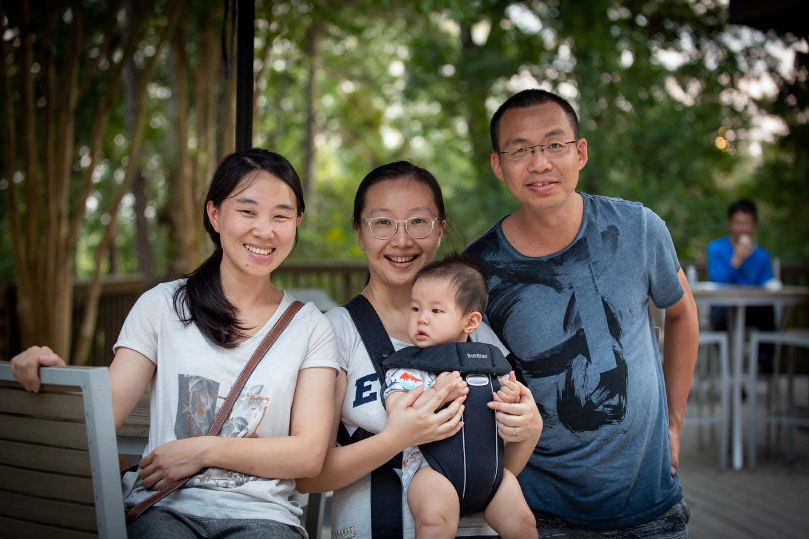 A group of people are posing for a picture with a baby in a carrier.