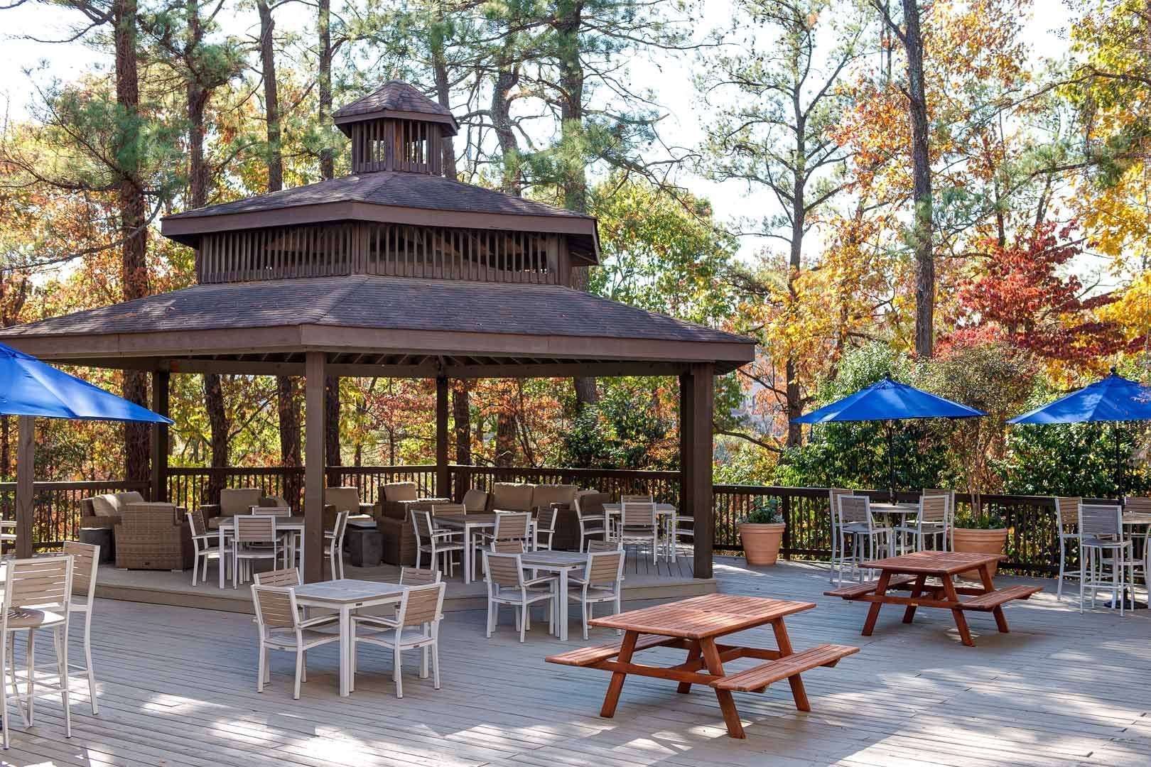 A gazebo with tables and chairs and umbrellas in front of it