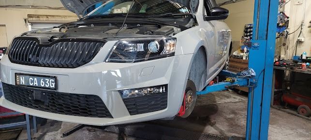 A White Car Is Sitting On Top Of A Blue Lift In A Garage β Albion Park Auto Electrical & Mechanical In Albion Park Rail, NSW
