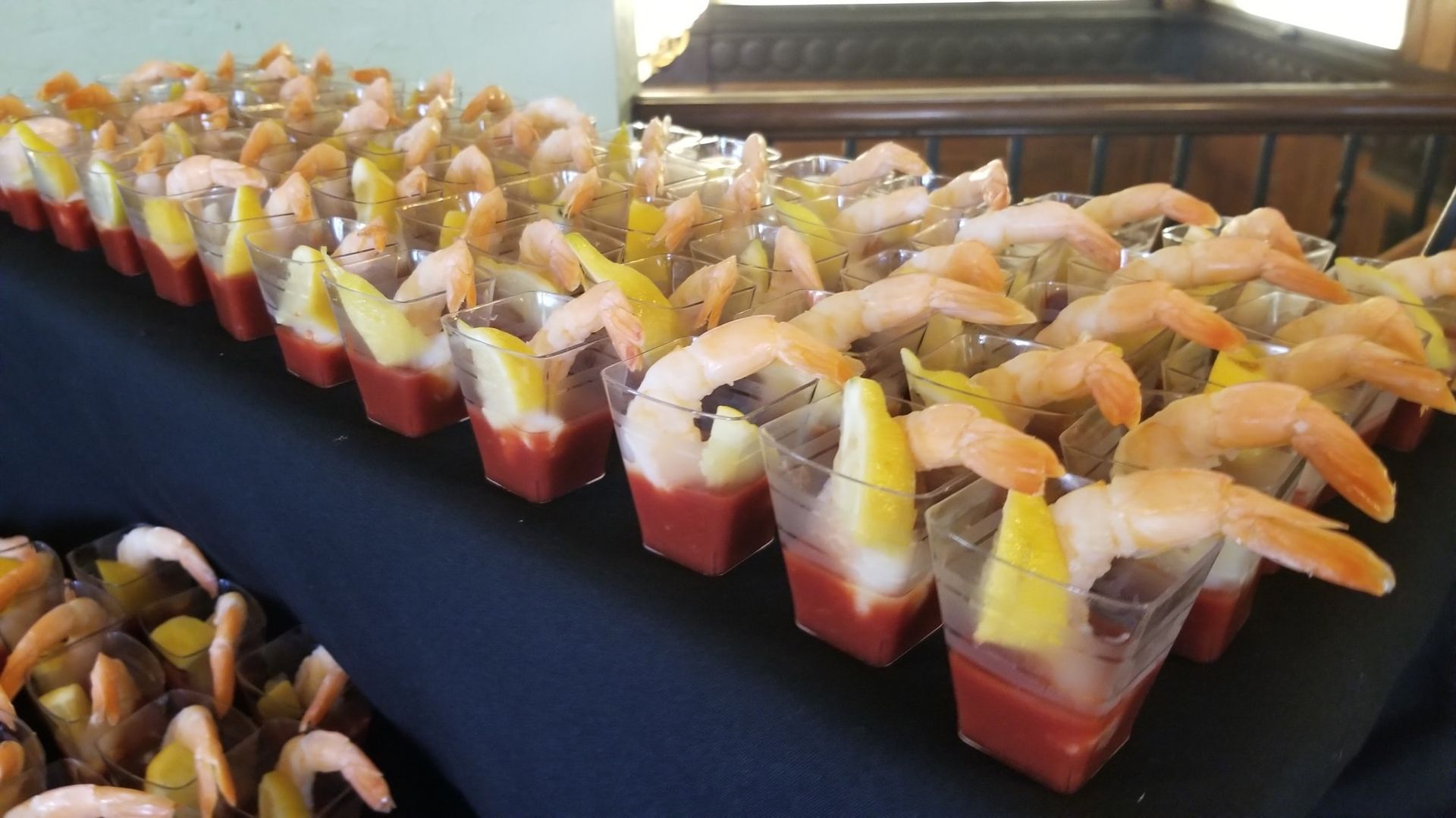 A row of cups filled with shrimp and tomato sauce on a table.