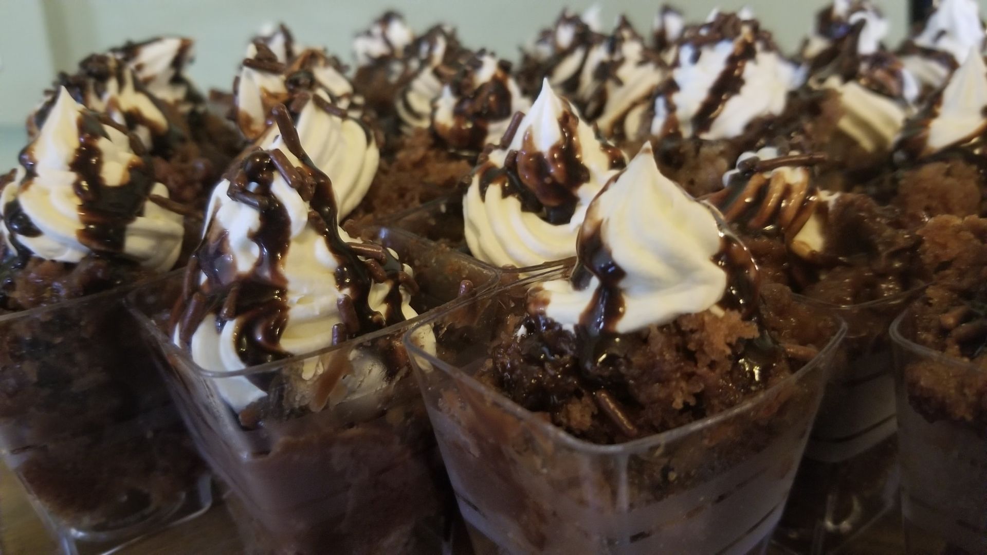 A row of cups filled with chocolate cake and whipped cream.