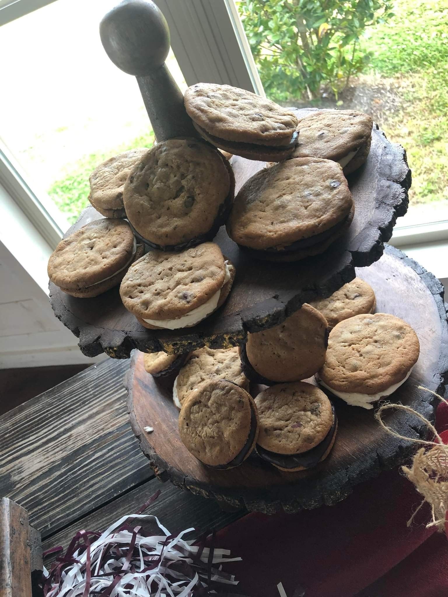 A wooden tray filled with cookies and sandwiches on a table.