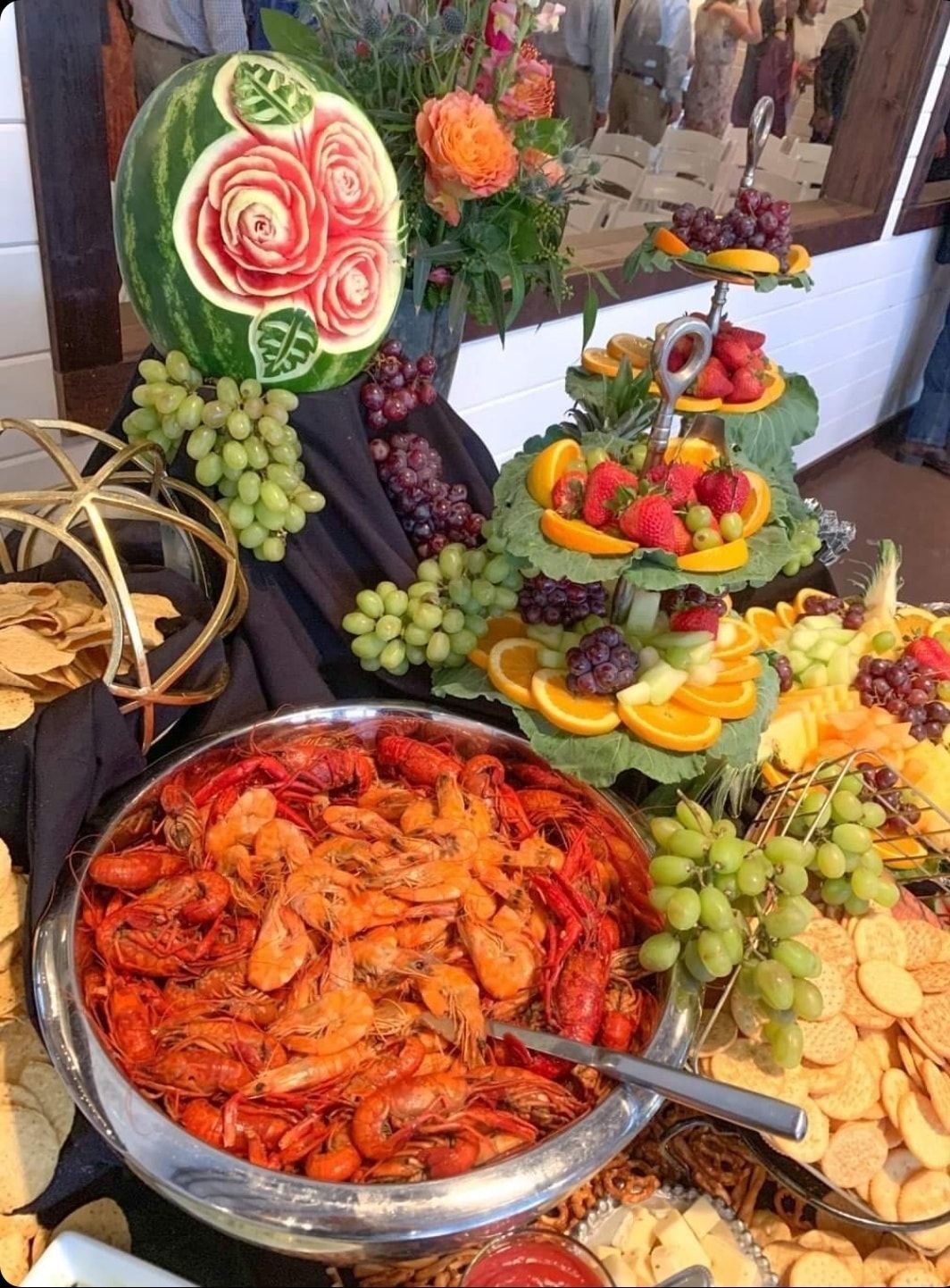 A buffet table with a bowl of shrimp and a watermelon carved into it.