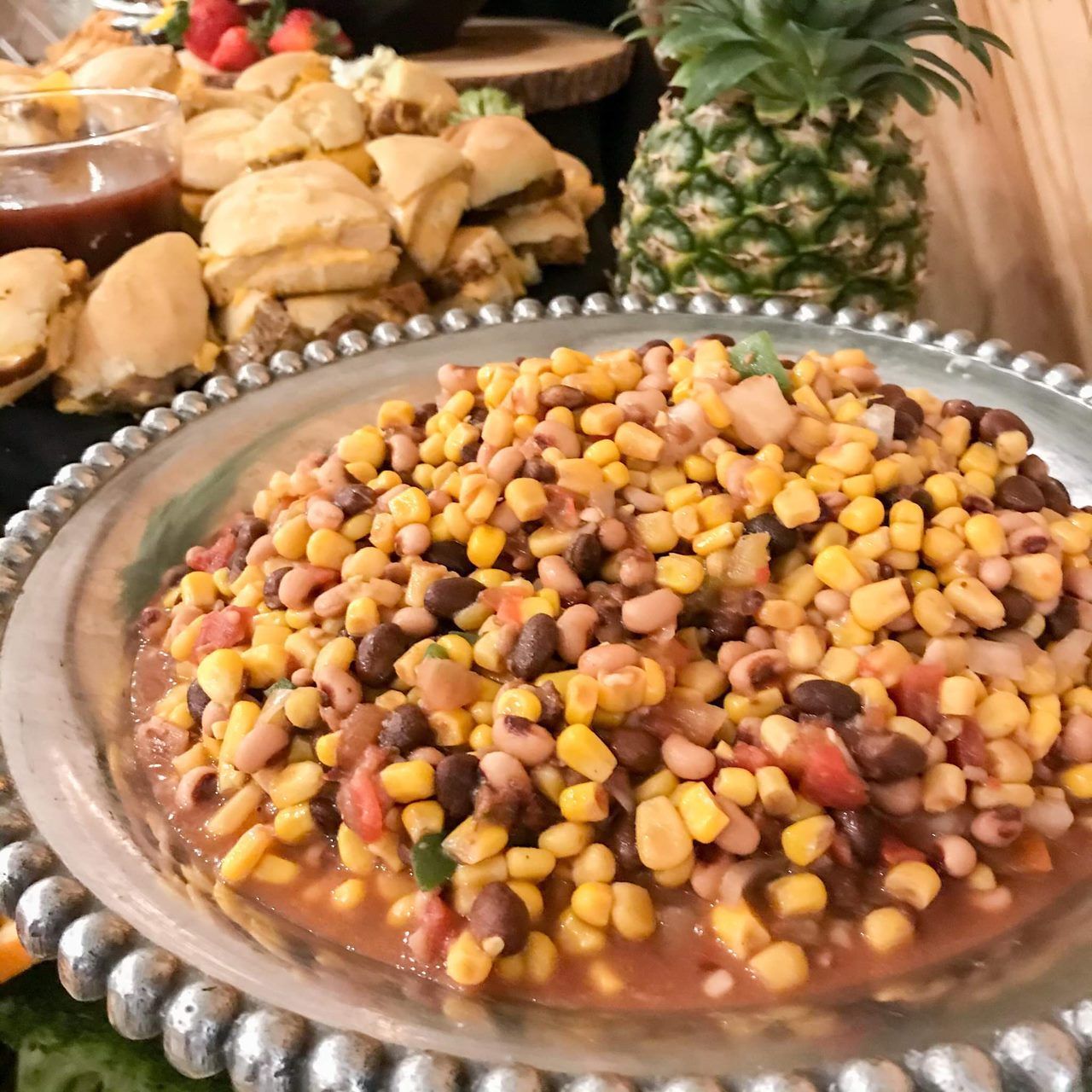 A plate of corn and beans with a pineapple in the background