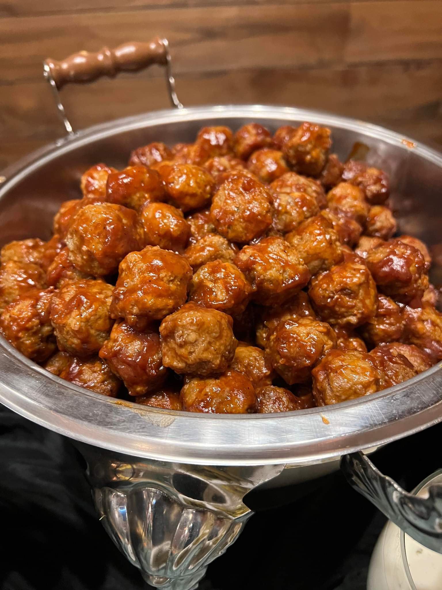 A bowl of meatballs in a barbecue sauce on a table.