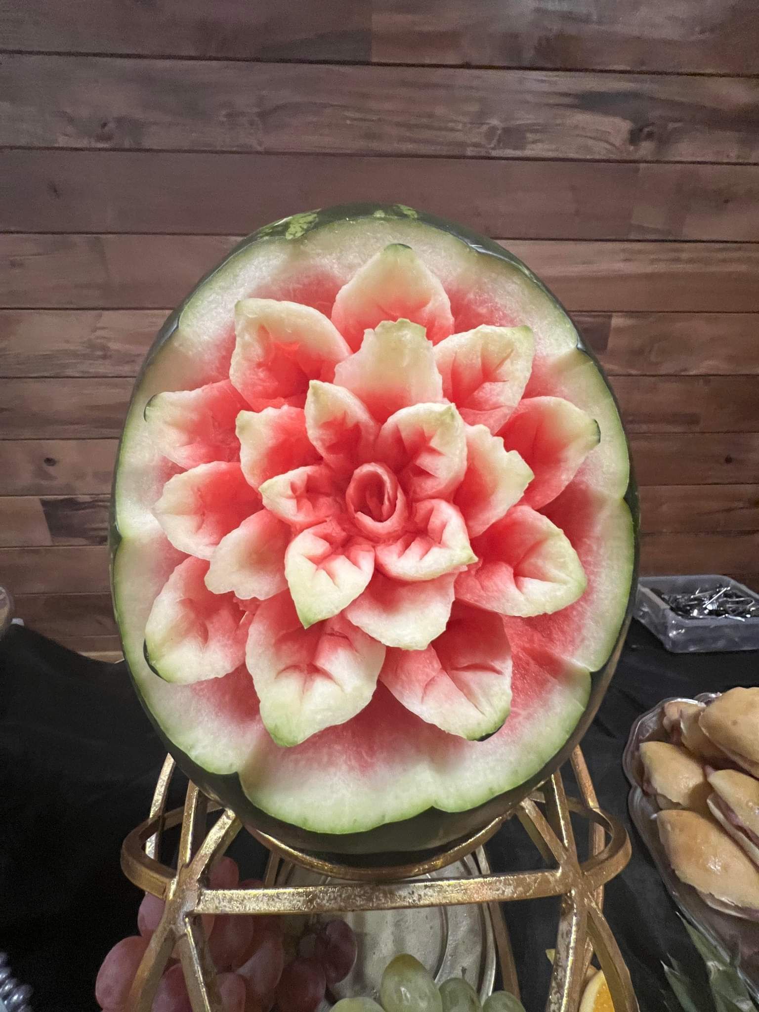 A watermelon carved into a flower is sitting on a table.